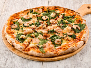 Seafood and Spinach Pizza loaded with fresh seafood, shrimp, spinach, and melted cheese served on wooden board side view of italian fast food