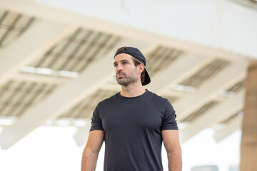 Portrait of a man in black cap and t-shirt standing under modern architecture