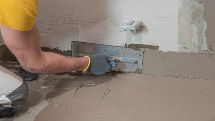 A worker's hand using a trowel for applies a  liquid membrane on the  the corner reinforcement tape...