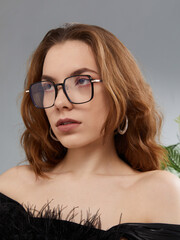 A glamorous woman in stylish glasses poses looking at the camera