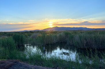 Swamp on mountain landscape at sunset in Spain. Marjal dels Moros Puçol. Lake in Park with bird watching spot. Nature reserve in Marjal de los Moros. Observatory of Tokens near Sagunto. Lake on sunset