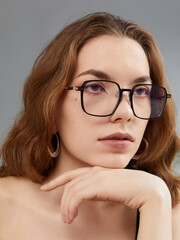 A glamorous woman in stylish glasses poses looking at the camera