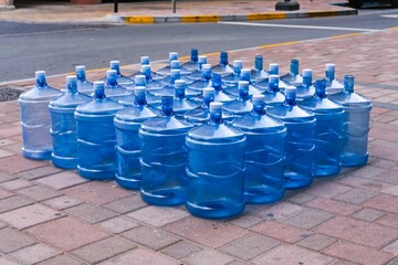 Bottled drinking desalinated water delivery in UAE. Empty refillable plastic drinking water bottles placed outside residential building for pickup.