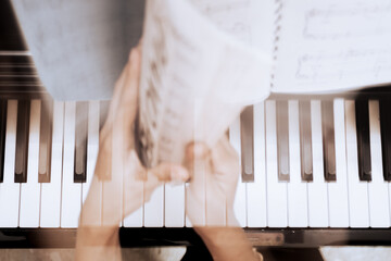 Top view of young adult female hands opening musical notation book choosing the right song to play on piano. Motion blur.