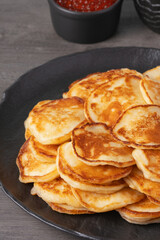 Delicious stack of golden pancakes served with cream and caviar on a rustic table