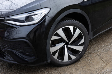 Close up winter tires on a road. Driving car with winter tire wheel on road. Detail of car tires in winter on the road. Headlight turning off switching of car LED headlights. New modern electric car