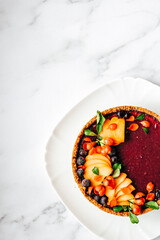 Cheesecake garnished with peach and black currant on a platter. View from above. Vertical