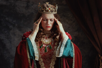stressed medieval queen in red dress having headache