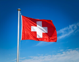 Simple Swiss flag, with its iconic red square and white cross, displayed vividly against a bright blue sky.