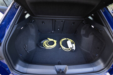 Electric car charger in car trunk. Trunk with charging cables. Modern interior. Portable in-cable...