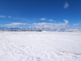 Fototapeta premium Snow covered prairie and Flatirons with blue sky in winter, Colorado