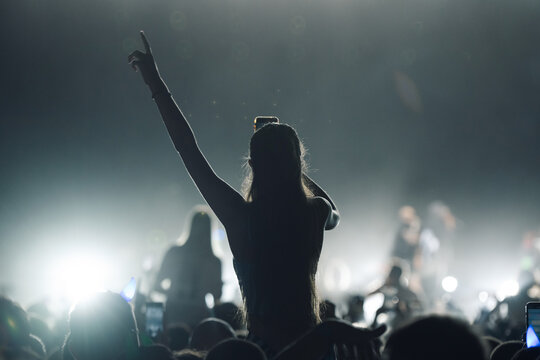 Young woman recording video with smartphone at concert