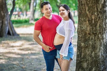 Obraz premium Portrait of beautiful pregnant latin couple looking at camera in a park