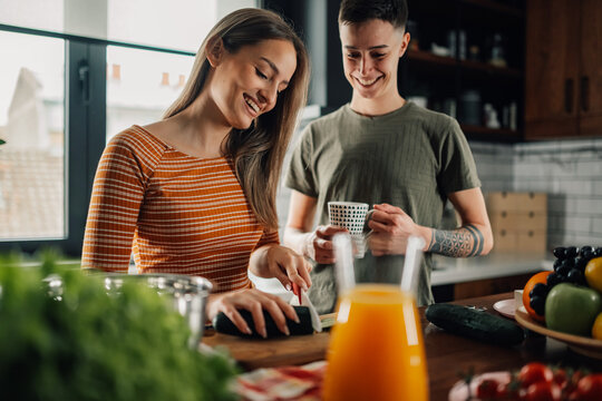 Lesbian couple preparing food and smiling in kitchen