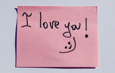 Pink sticky note with handwritten 'I love you!' message and smiley face