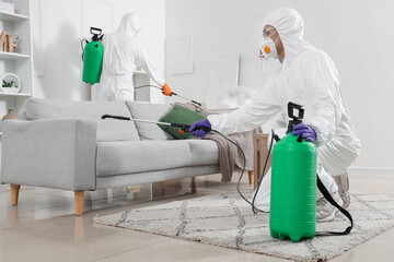 Male workers in hazmat suits disinfecting room