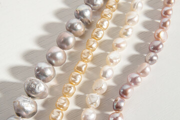 Pearl threads or necklaces on white background. Different types of natural pearls