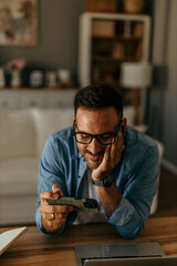 Bright and airy setting: Man gaming on his phone with earphones in a contemporary home