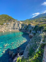 A bay on the island of Mallorca, with cliffs, mountains, and a blue sky.