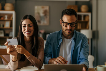 Couple planning their finances while sitting at a sleek table with a laptop