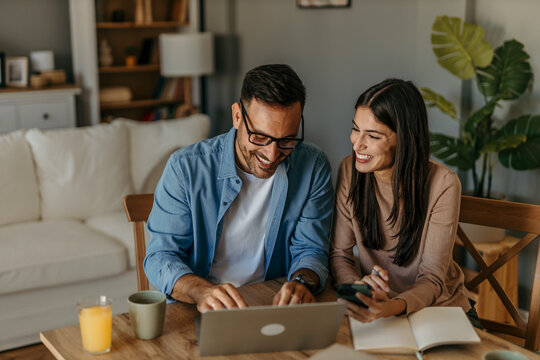 Couple working on home finances together at a table in a bright, modern living room
