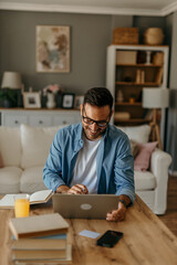 Smiling man managing personal finances online from his bright and modern living room
