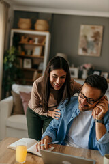 Bright and modern. Duo focused on a laptop at the table in a cozy space