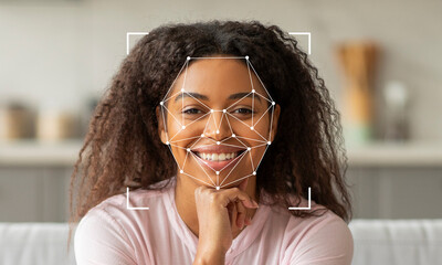 A woman with curly hair is smiling confidently while facial recognition technology detects her...