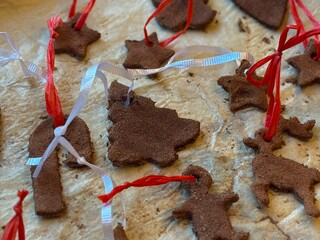 Close up of homemade cinnamon dough ornaments in different shapes, including a gingerbread man, candy cane, Christmas tree, a reindeer, and stars. Perfect for holiday decorations or handmade gifts.