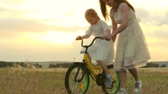 happy family. child girl learning ride bike. mom daughter kid spend time bike park. concept children dream. mother child play outdoors. little girl pedals steers bicycle park. young mother with kid