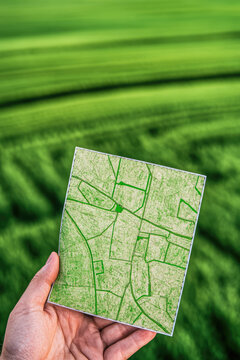 Cadastral map in hand on field background. Sale of building plot of land for house construction. Plan of future land plots