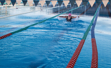 Competitive swimmer woman practicing butterfly stroke in a pool open water during afternoon training session