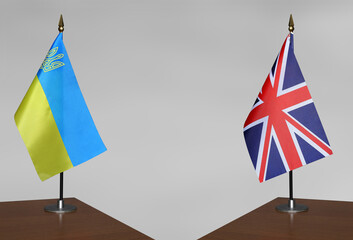 Table flags of Ukraine and United Kingdom on a gray blurred background
