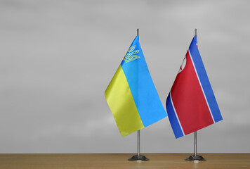 Tabletop flags of Ukraine and North Korea on a gray blurred background