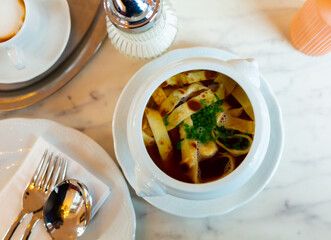 Just cooked fresh portion of German soup, Frittatensuppe, served in bowl on table.