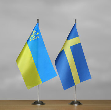 Tabletop flags of Ukraine and Sweden on a gray blurred background