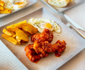 Appetizing breaded chicken served with fried eggs and baked potato