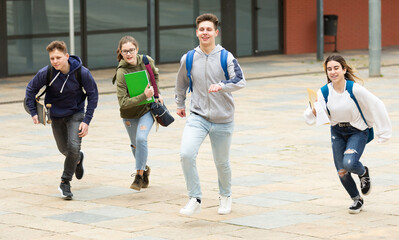 Group of teenagers running on city street and having fun