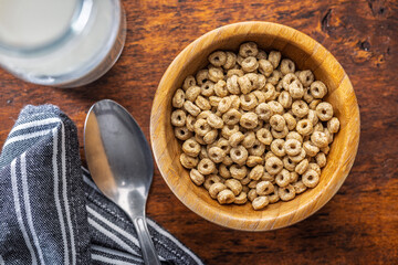 Sweet honey cereal rings in bowl on wooden table. Top view.