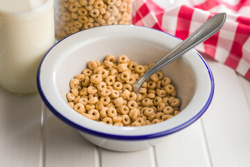 Sweet honey cereal rings in bowl on white table.