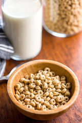 Sweet honey cereal rings in bowl on wooden table.