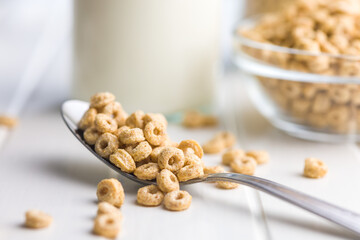 Sweet honey cereal rings on spoon on white table.