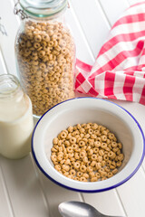 Sweet honey cereal rings in bowl on white table.