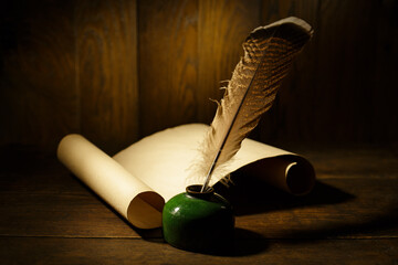 Ancient paper scroll with feather on old wooden table. Feather for calligraphy, old education,...