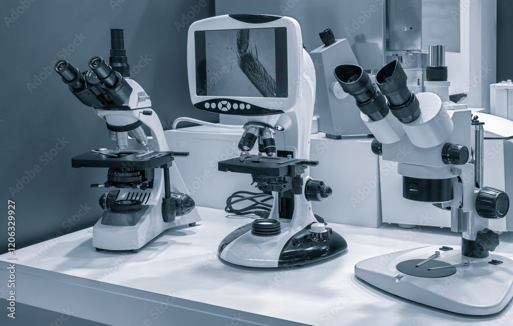 Poster three microscopes are on a table, one of which has a screen. the other two are not equipped with scr