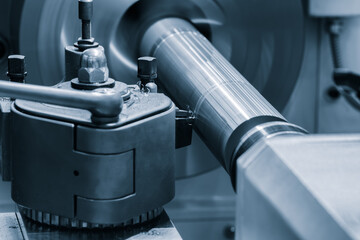 A lathe machine is grinding a piece of metal. The grinding wheel is spinning rapidly, and the metal...