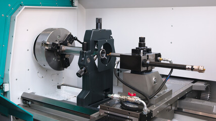 A cnc machine is being used to cut a piece of metal. The machine is black and silver.