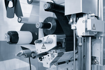 Fragment of the conveyor of sticking labeling machine. Abstract industrial background.