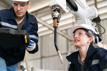 Engineers collaborating on industrial robot setup in a manufacturing facility during daytime