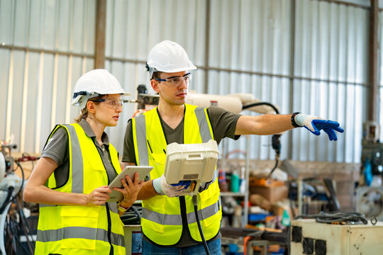 Workers collaborate on industrial project with portable device in factory setting